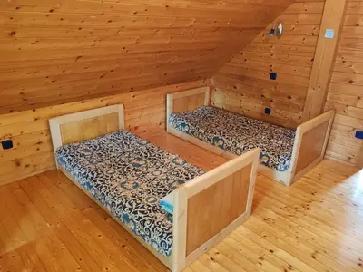 two beds in a room with wooden walls and wood floors at Room Janez in Preddvor
