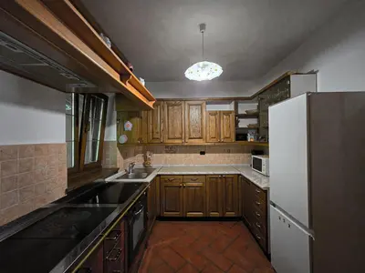 a kitchen with wooden cabinets and a white refrigerator at Apartma Maln in Kobarid