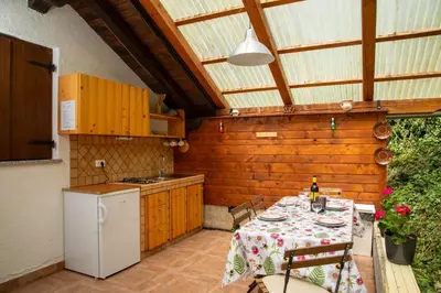 a patio with a table and a kitchen with aperature at Apartma Maln in Kobarid