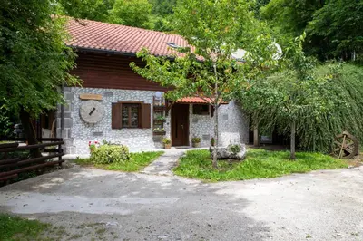 a small stone house with a tree in front of it at Apartma Maln in Kobarid