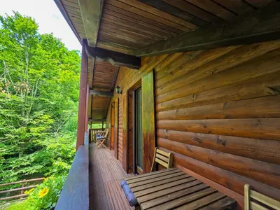 a porch of a wooden cabin with a bench on it at Apartma Maln in Kobarid