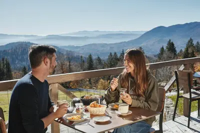 a man and woman sitting at a table eating food at Glamping Zarja, Vipava Valley in Zoll