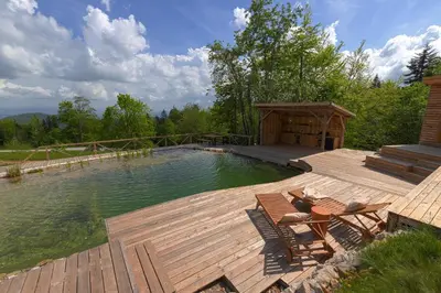 a swimming pool with a wooden deck and a gazebo at Glamping Zarja, Vipava Valley in Zoll