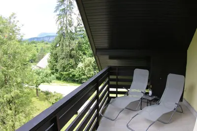 two white chairs sitting on a balcony with a view at Aparthouse Bohinj in Bohinj