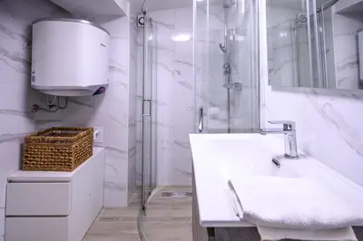 a white bathroom with a shower and a sink at The Darling Loft in Ljubljana
