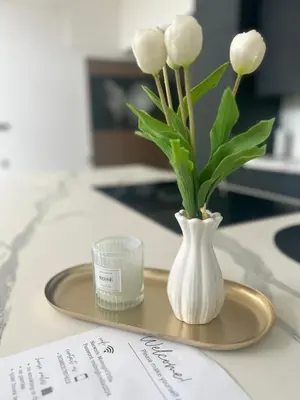 a vase of white flowers on a plate with a candle at Midnight Villa in Cerkvenjak