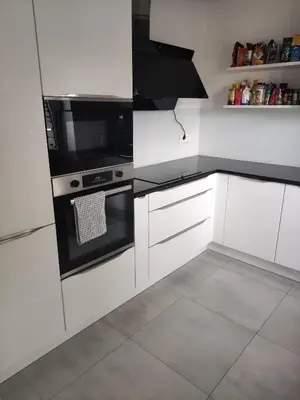 a kitchen with white cabinets and black appliances at Apoteka in Lenart v Slovenskih Goricah