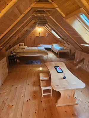 a room with two beds and a table in a attic at Cottage Ladybug in Mojstrana