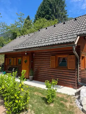 a wooden cabin with a yellow door in a yard at Cottage Ladybug in Mojstrana
