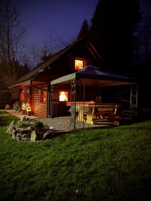a log cabin with an umbrella in front of it at night at Cottage Ladybug in Mojstrana
