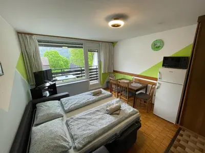 a bedroom with two beds and a table and a refrigerator at Apartma Marjeta in Bovec