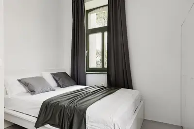 a bed in a white room with a window at Apartments Mazijeva in Ljubljana