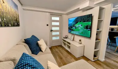 a living room with a couch and a tv on a wall at Relax apartment Ljubljana in Ljubljana