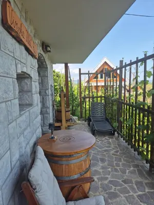 a patio with a wooden table and a stone wall at RELAX HOUSE Kolpa view Podzemelj in Gradac