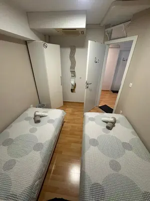 two beds in a room with white cabinets and a hallway at Granada Rooms in Ljubljana