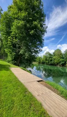 a walkway next to a tree next to a body of water at BIG BERRY KOLPA - KIWI mobile house, Metlika in Gradac