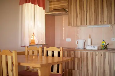 a kitchen with a wooden table and a table and chairs at Tourist Farm Apartments Lovrec in Jiršovci