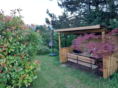 a wooden bench in a garden with a gazebo at Starling Loka in Škofja Loka