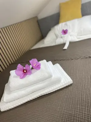 two white towels with purple flowers on a bed at Wellness Počitniška hiša Manja in Ljutomer