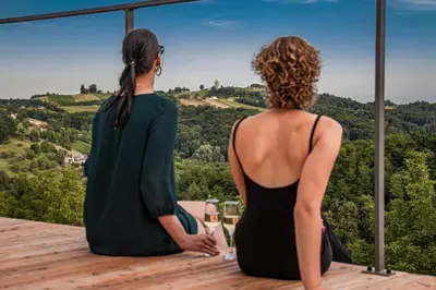 two women sitting on a deck looking out at the mountains at Wellness Počitniška hiša Manja in Ljutomer