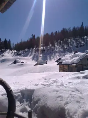 a snow covered field with houses and a beam of light at Hiška vogar in Bohinj