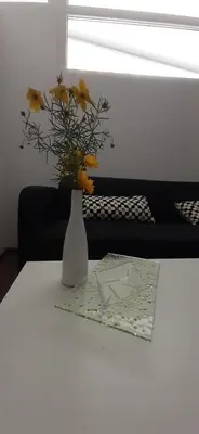 a white vase with yellow flowers on a table at apartma pika in Šempeter pri Gorici
