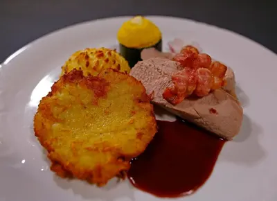 a white plate of food with meat and sauce at Apartments at Gostilna Martin in Trbovlje