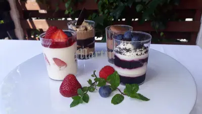 three desserts in glasses on a table with strawberries and blueberries at Apartments at Gostilna Martin in Trbovlje