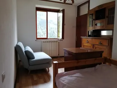 a bedroom with a bed and a chair and a window at Hikers Hut Hišar in Podbrdo
