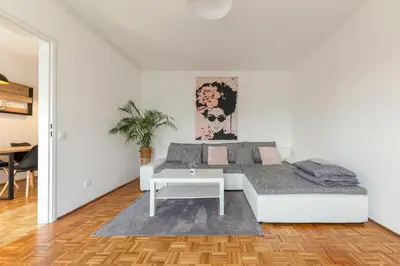 a white bedroom with a bed and a table at Cosy and Bright Apartment in Ljubljana