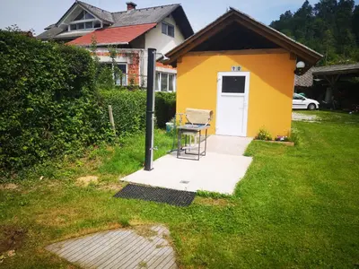 a yellow house with a table and a chair in a yard at Počitniška prikolica Zeleni raj in Podnart