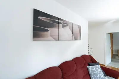 a red couch in a living room with a picture on the wall at Apartments BUMM in Ljubljana