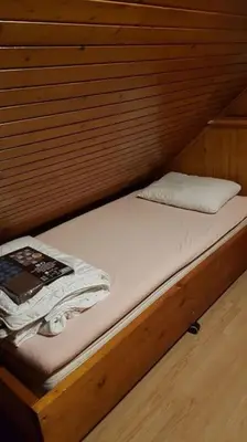 a bed in a wooden cabin with a book on it at Chalet Kujavnk in Kranj