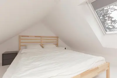 a bedroom with a bed with white sheets and a window at Studio Nensi in Ljubljana
