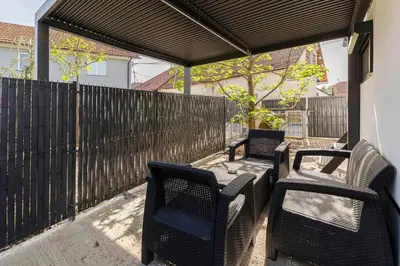 a patio with three chairs and a table and a fence at Tiny House Ljubljana in Ljubljana