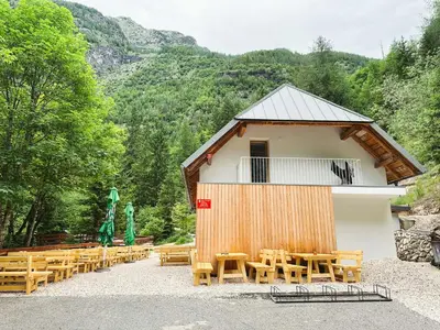 a group of wooden tables and chairs in front of a building at Koča ob izviru Soče in Trenta