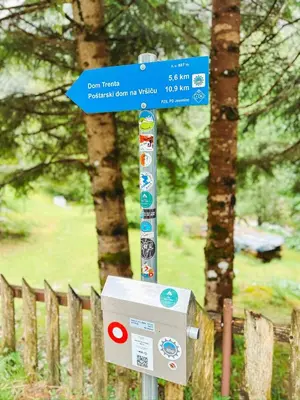 a street sign in a park next to a fence at Koča ob izviru Soče in Trenta