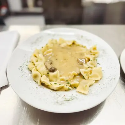 a plate of pasta with mushroom sauce on a table at Koča ob izviru Soče in Trenta