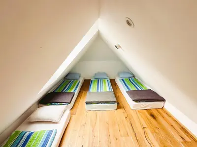 three bunk beds in a attic with wooden floors at Koča ob izviru Soče in Trenta