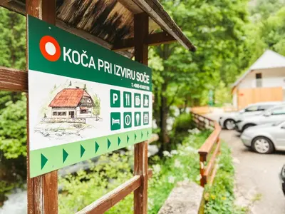 a sign on a fence with a house at Koča ob izviru Soče in Trenta