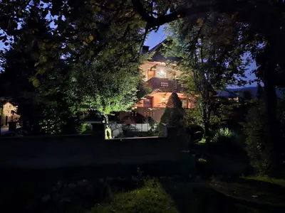 a large house is seen through the trees at Apartma Bistr'ca in Bohinj