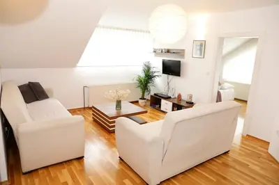a living room with two white chairs and a table at Holiday Home Slavc with 4 Bedrooms in Brežice