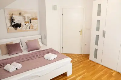 a white bedroom with a large bed with two pillows at Holiday Home Slavc with 4 Bedrooms in Brežice