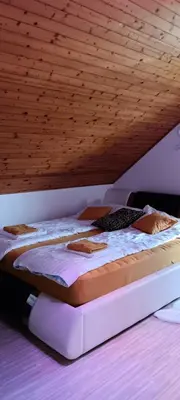 a bed in a room under a wooden ceiling at Hiša Piber in Bled