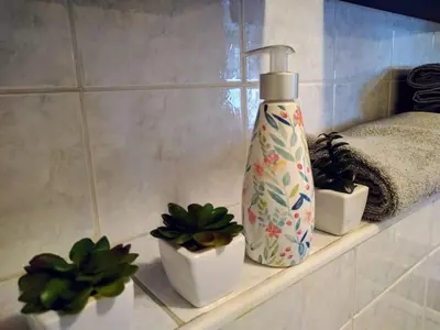 a shelf with a bottle and three plants on it at Stylish Boutique Apartment in Ljubljana