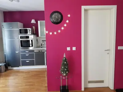 a kitchen with a pink wall with a clock and a christmas tree at Stylish Boutique Apartment in Ljubljana