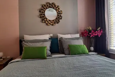 a bedroom with a bed with green pillows and a mirror at Stylish Boutique Apartment in Ljubljana