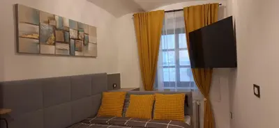 a room with a couch with yellow pillows and a window at Studio apartment Under the castle in Škofja Loka