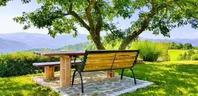 a wooden bench with a picnic table in a park at Heaven Can Wait Country Retreat in Poljane nad Škofjo Loko