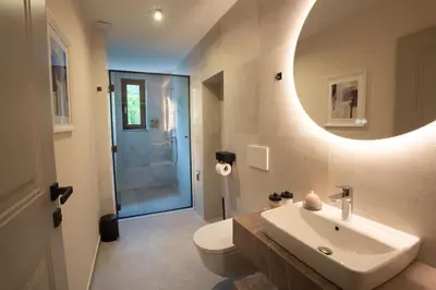 a bathroom with a sink and a toilet and a mirror at Kalan Boutique Stay in Žirovnica